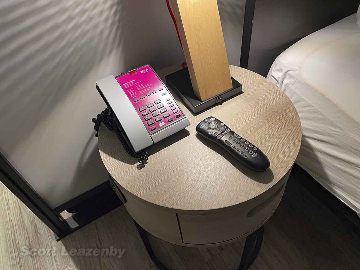 Nightstand with lamp, telephone, and remote control