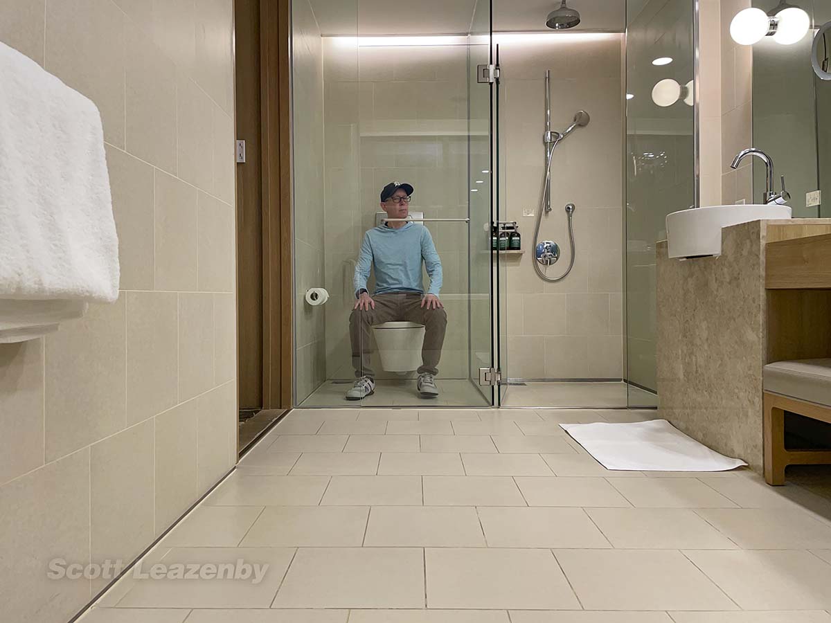 Scott sitting on the toilet in his suite at the Crowne Plaza Hotel Changi airport